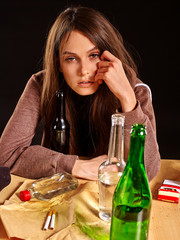 Drinking girl in heavy depression drinking alcohol and smokes cigarettes in solitude. Drinking habits. Girl is heavy drinkers. Girl head prop hand and looks in camera on black background.