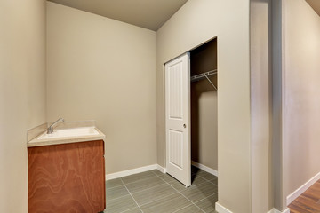 Empty beige laundry room with sink and closet