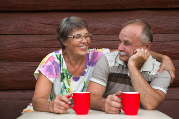 Adorable senior couple outdoors drinking from mugs

