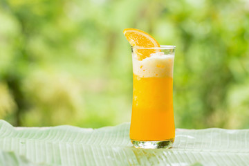 Glass of Orange Smoothie on garden background