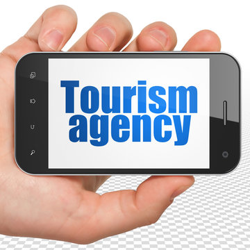 Vacation concept: Hand Holding Smartphone with Tourism Agency on display