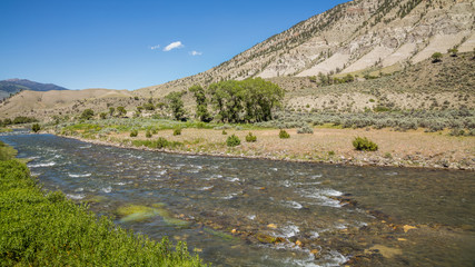Fototapeta na wymiar Fast flowing river on the background of the rocky coast. Dark blue rough river. Scenic landscape at Boiling River Trail, Yellowstone National Park, Wyoming