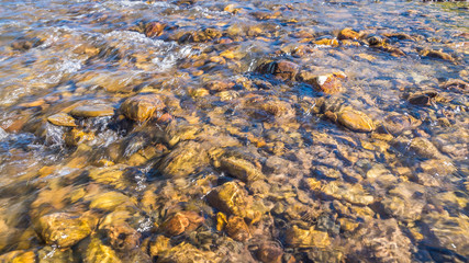 The bottom of the river close-up. The flow of water among the rocks. Beautiful brown stones on the river bottom. Boiling River Trail, Yellowstone National Park, Wyoming
