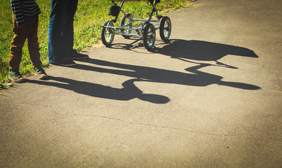 Motherhood concept- shadow of young mother holding little son and stroller