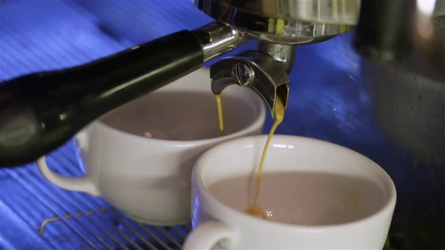 Professional coffee machine prepares coffee in two cups.