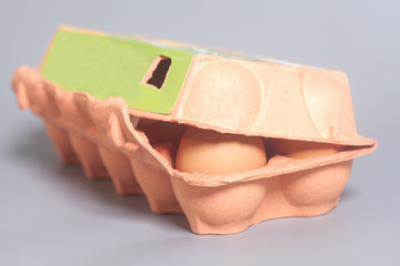 Cardboard egg box with brown eggs on gray background