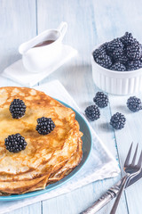 Crepes with blackberries on the wooden table