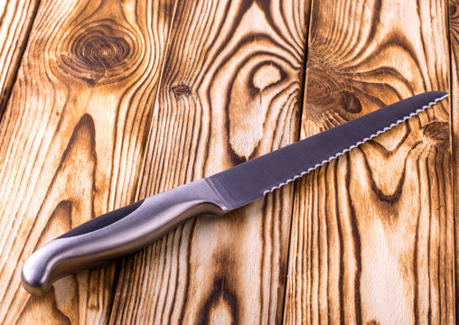 shiny metal kitchen knife for cutting bread on wooden table