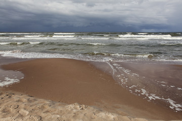 Fototapeta na wymiar Stormy sea waves, dark sky and sand.