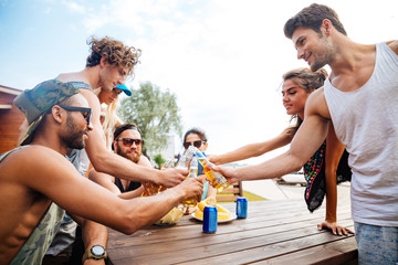 Happy young people with beer celebrating together outdoors
