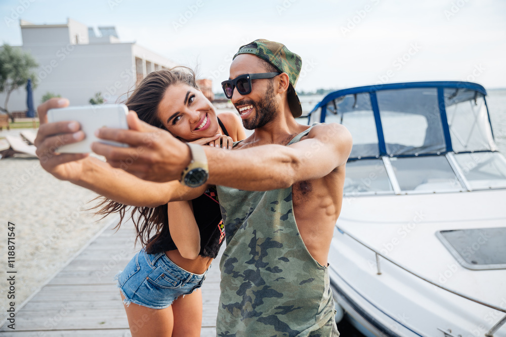 Wall mural Portrait of a happy couple making selfie photo on smartphone