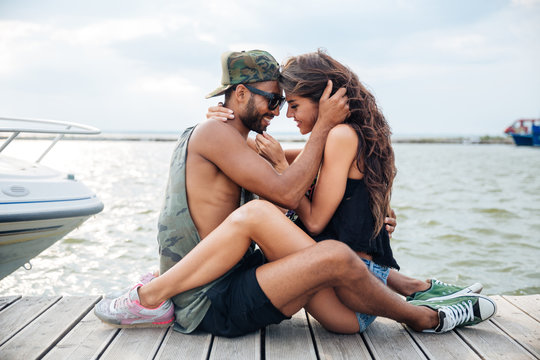 Couple in love sitting and kissing at wooden sea pier
