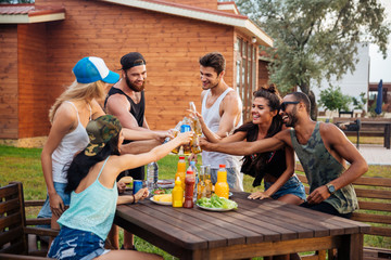 Group of young cheerful friends having fun at picnic outdoors