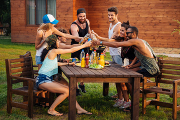 Happy people celebrating and drinking beer at the table outdoors