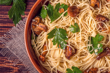Pasta spaghetti with chanterelles mushrooms on wooden background