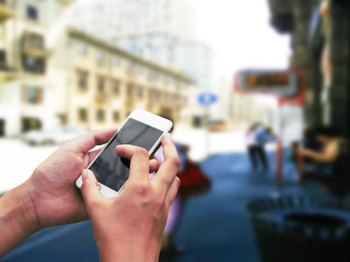 Hand hold and touch screen smart phone,on city blur.