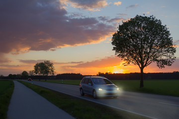 Autofahrt mit Abblendlicht in der Dämmerung bei Sonnenuntergang
