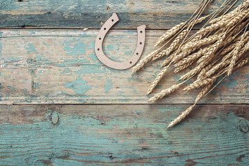 Background with ears of wheat and decorative horseshoe on old bl