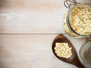 Glass jar with oat-flakes on the wooden background. View from above