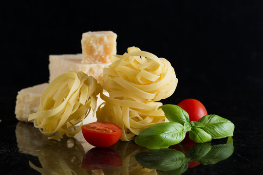 Pasta Tagliatelle arranged on marble table. Raw closeup background. Delicious dry uncooked ingredient for traditional Italian cuisine dish. Top view. Copy space