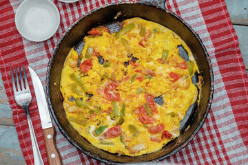 Omelette with vegetables in pot on red white napkin