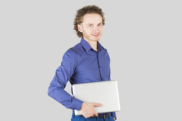 Smiling intelligent man with laptop in hand in studio on gray background. Modern lifestyle.