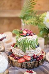Wedding cake in rustic style with strawberries decorated with fern