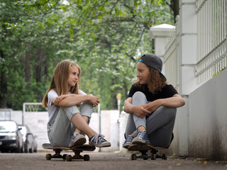 Teen girl talking while sitting on skateboards
