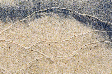 Fototapeta na wymiar Abstract pattern of waves on a sandy beach