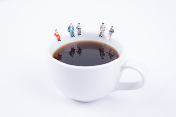 miniature people business team sitting on white coffee cup having a coffee break. business idea concept
