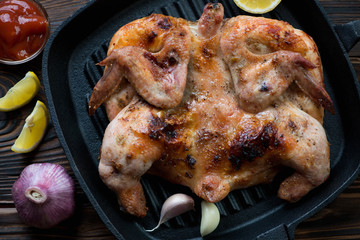 Close-up of chicken tabaka on a cast-iron grill pan, top view