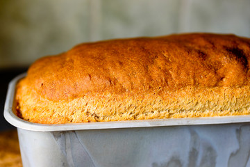 Shallow focus home baked bread still in aluminum baking pan. Golden brown crust with just the right...