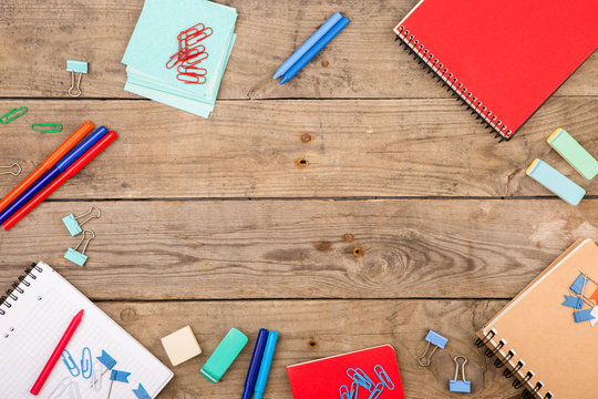 Notepads, papers, markers and other stationery on brown wooden table