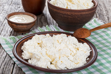 cottage cheese on dish with spoon and cream in bowl