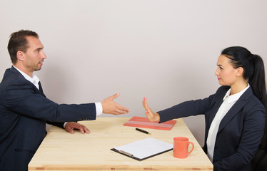 Businessman extending arm for handshake, businesswoman stopping him