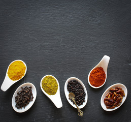 Spices in the spoons over a black stone