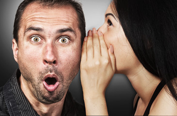 Woman sharing secret with surprised man - obrazy, fototapety, plakaty
