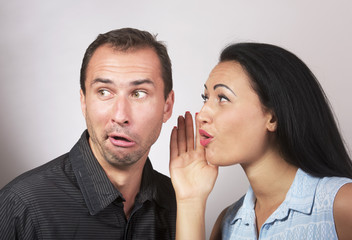 Woman sharing secret with surprised man