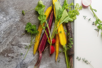 Ripe black, orange and yellow carrots, radish with parsley and t