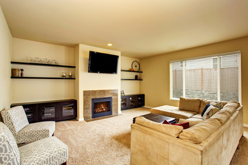Living room in beige tones with carpet floor and fireplace.
