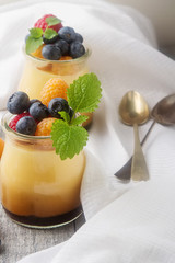 Milk Caramel dessert in a glass jar with berries, mint. Gray woo