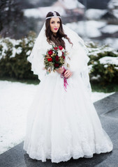 Fototapeta na wymiar Bride looks kicky dressed in luxuriant dress and crystal wreathe