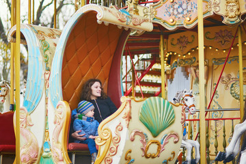 Fototapeta na wymiar Mother with her little son on merry-go-round in Paris