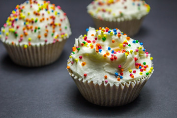 Colorful sweet cupcake with cream on black background