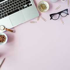 Flat lay, top view office table desk frame. feminine desk workspace with succulent, laptop, glasses, diary and golden clips on pink background.