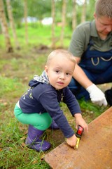 Little son helping his father with building work