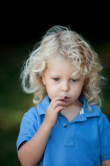 Pensive boy three year old with long blond hair