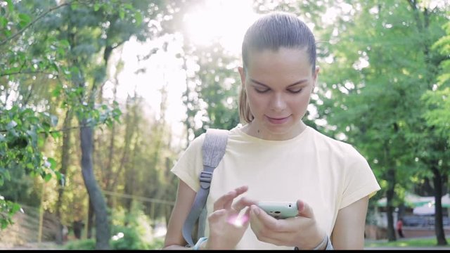 Young Pretty Woman Enjoys A Smartphone In The Park In The Summer, A Low Camera Angle, Lens Flare