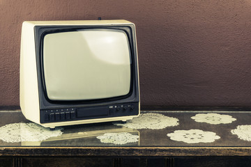 Old retro TV on vintage table, brown background