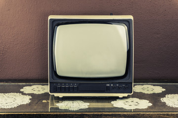 Old retro TV on vintage table, brown background